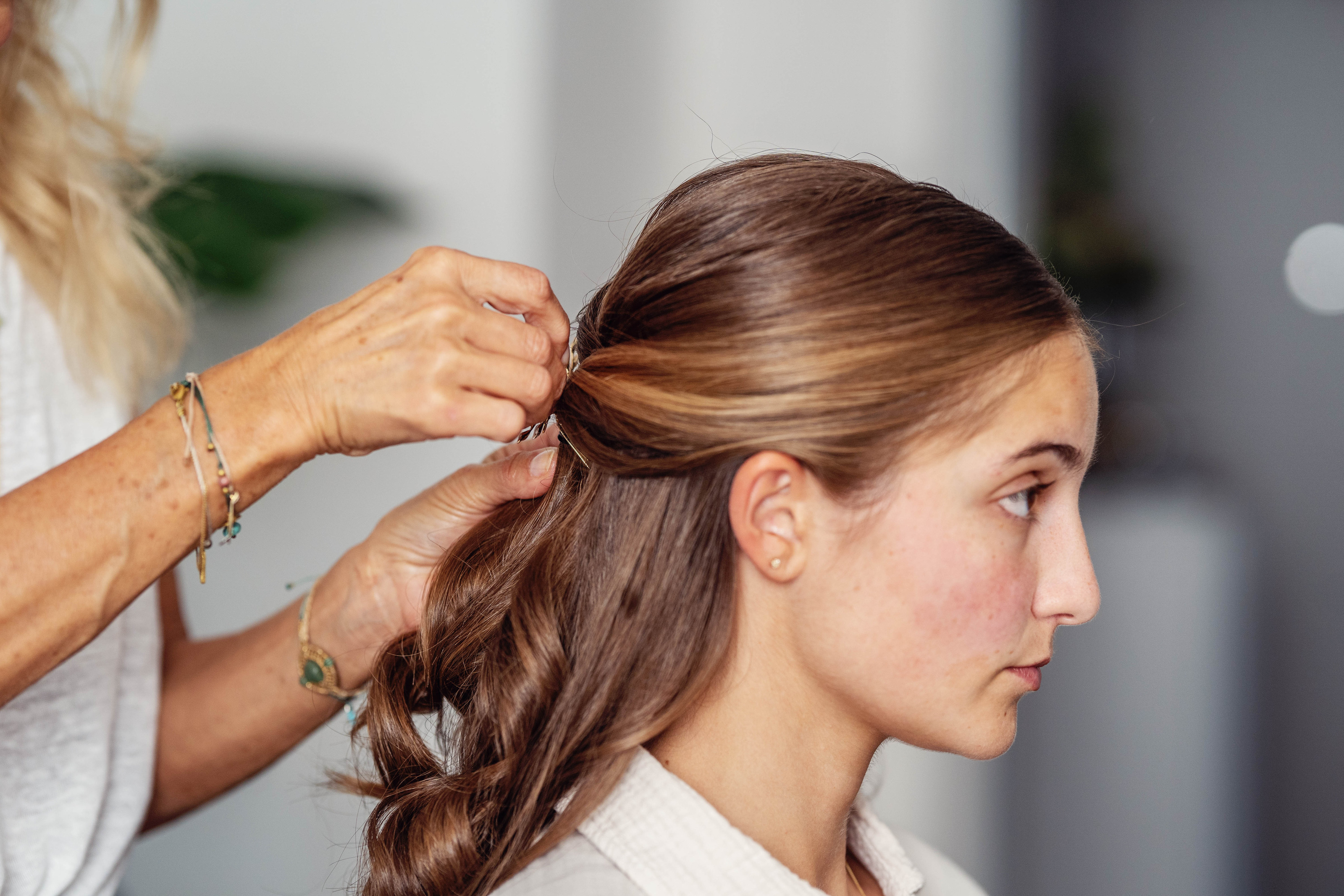 Hochzeitsfotograf Bielefeld – Friseurin steckt der Braut sorgfältig die braunen Haare beim Getting Ready