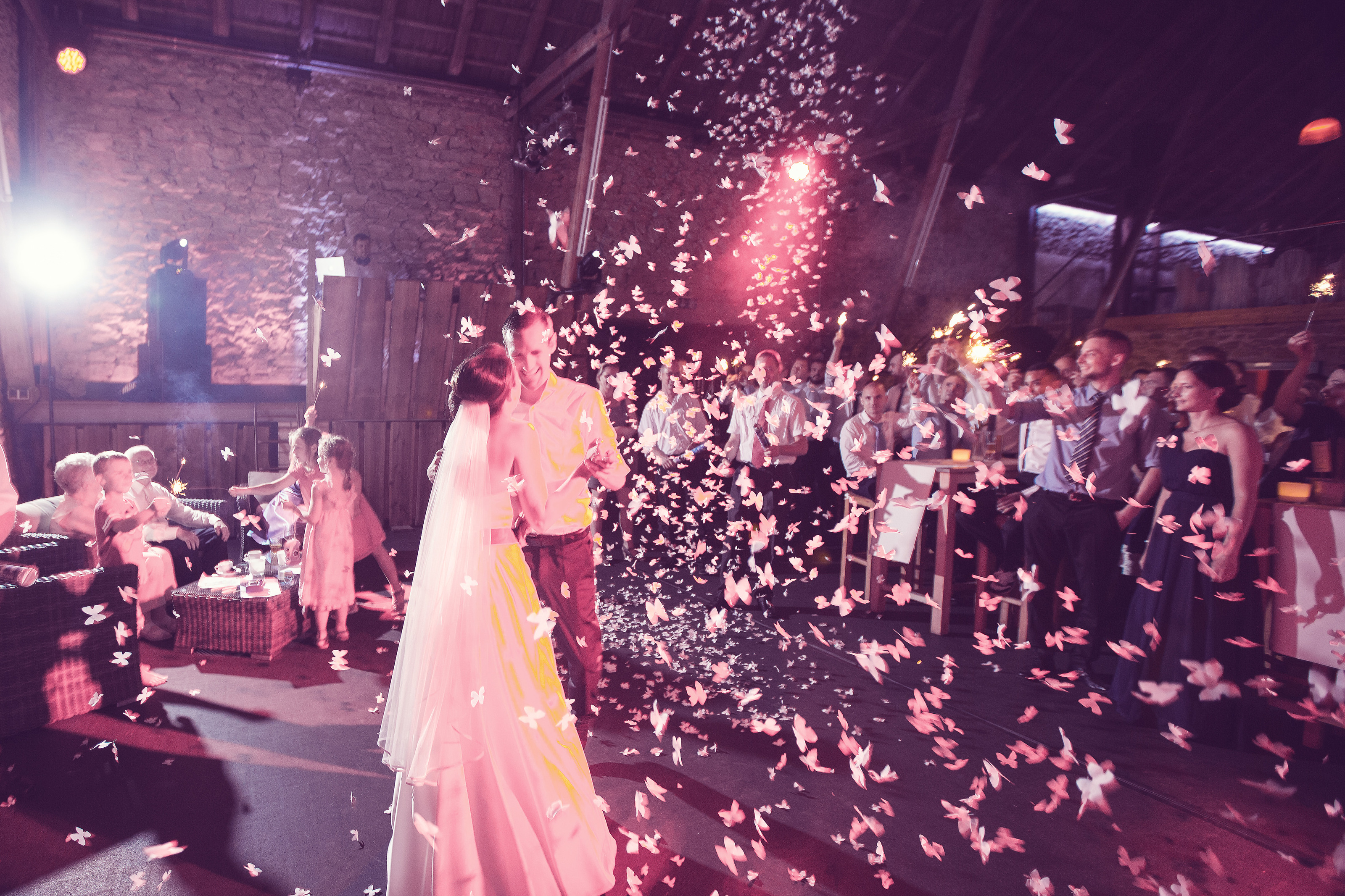 Hochzeitsfotograf Bielefeld – Brautpaar beim Eröffnungstanz, weiße Papierschmetterlinge regnen herab, Hochzeitsgesellschaft schaut zu