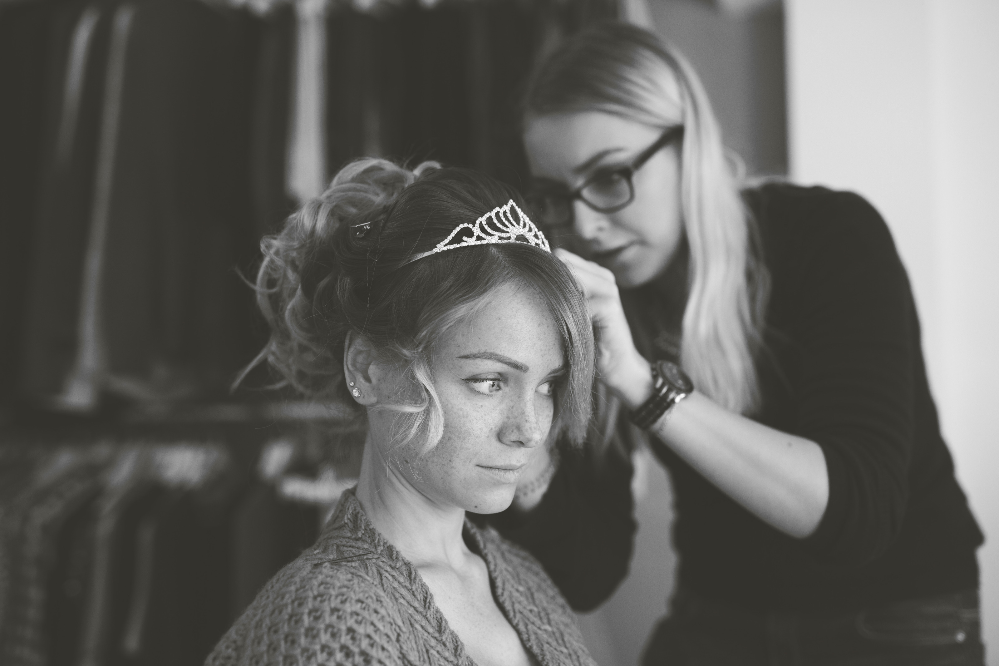 Hochzeitsfotograf Bielefeld – Schwarz-Weiß: Friseurin setzt der Braut beim Getting Ready ein Diadem in die Hochsteckfrisur