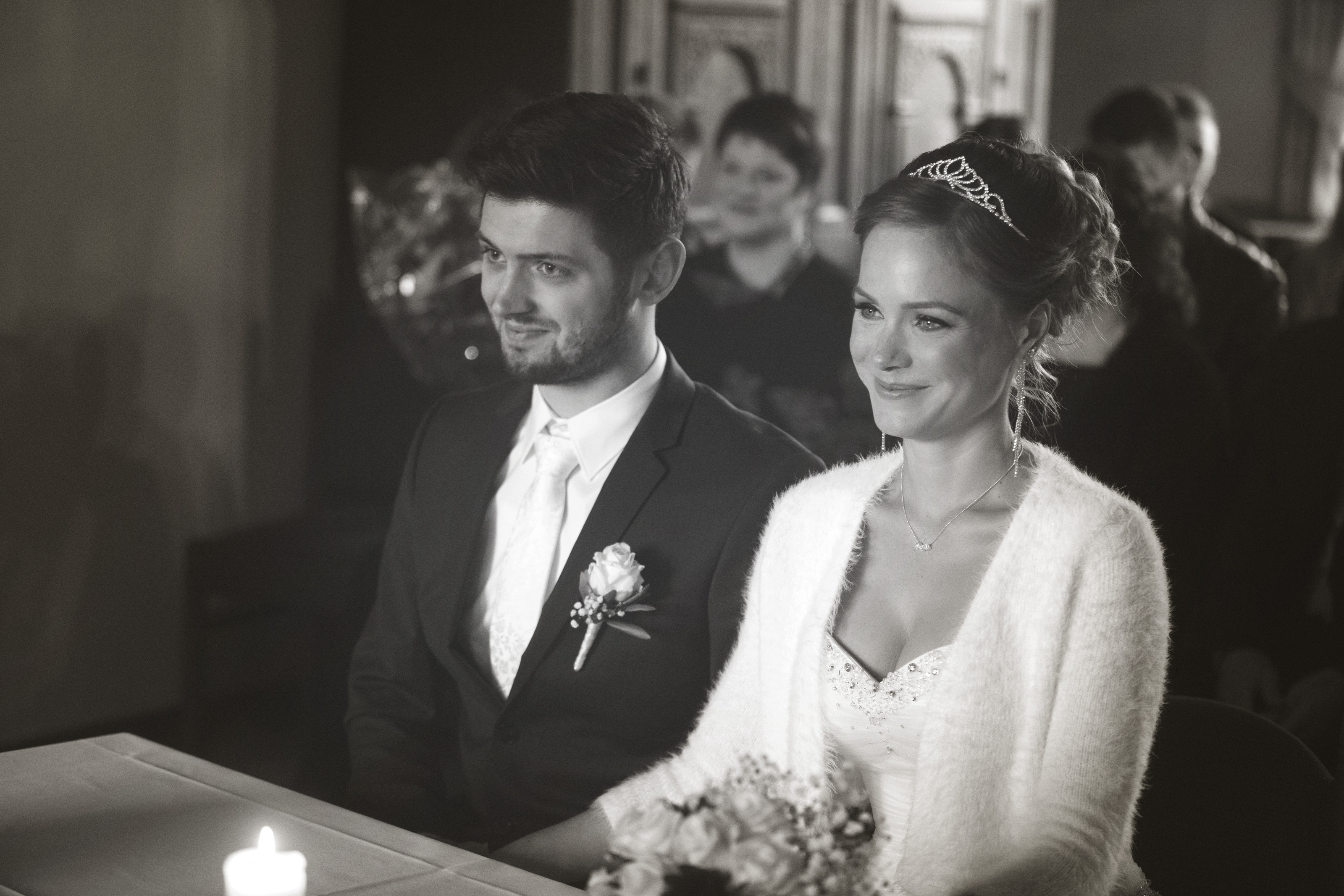 Hochzeitsfotograf Bielefeld – Schwarz-Weiß: Brautpaar sitzt beim Standesamt, Braut lächelt glücklich, Bräutigam mit Boutonniere