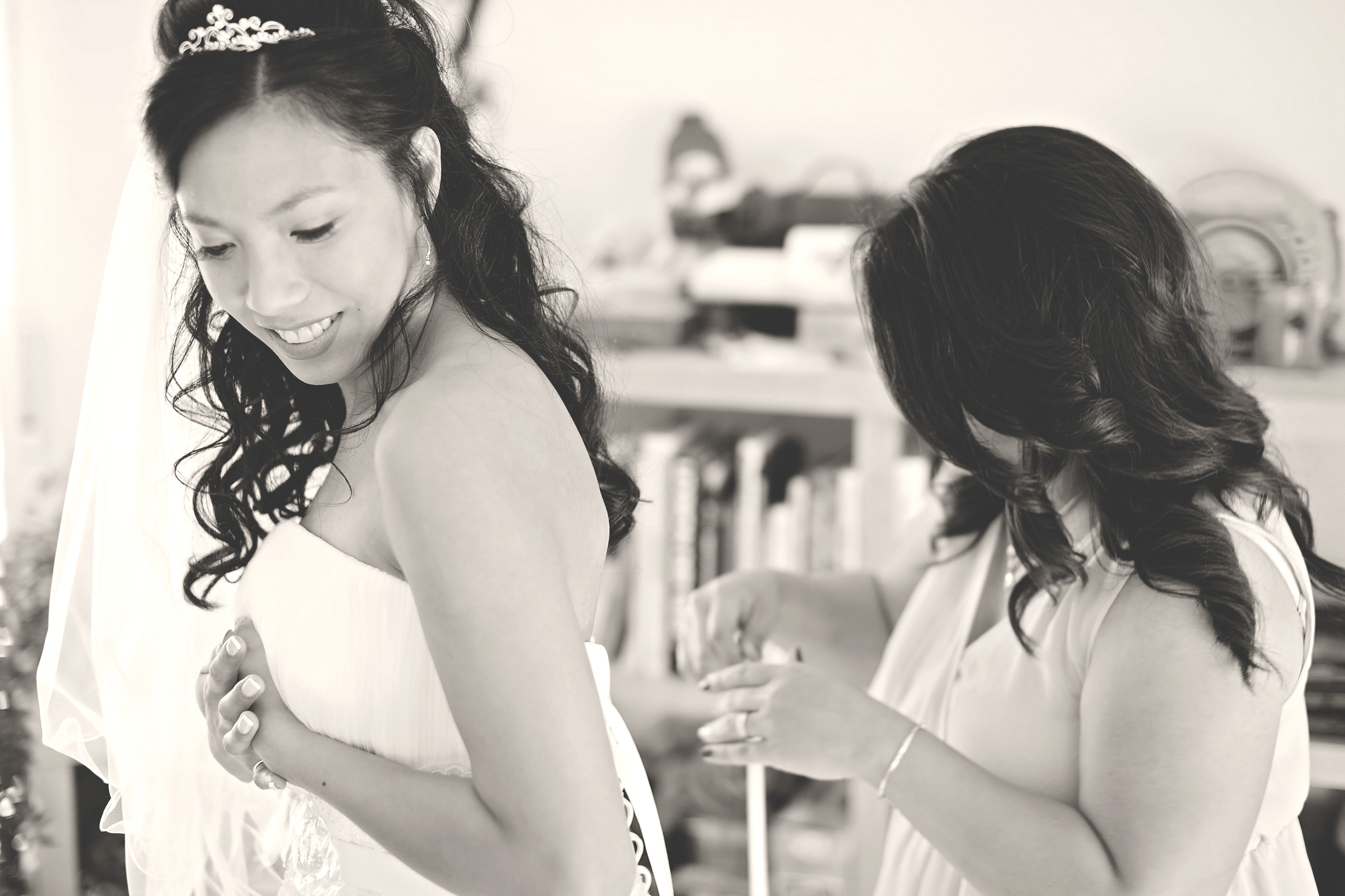 Hochzeitsfotograf Bielefeld – Schwarz-Weiß: Freundin hilft der Braut beim Schließen des Brautkleides beim Getting Ready