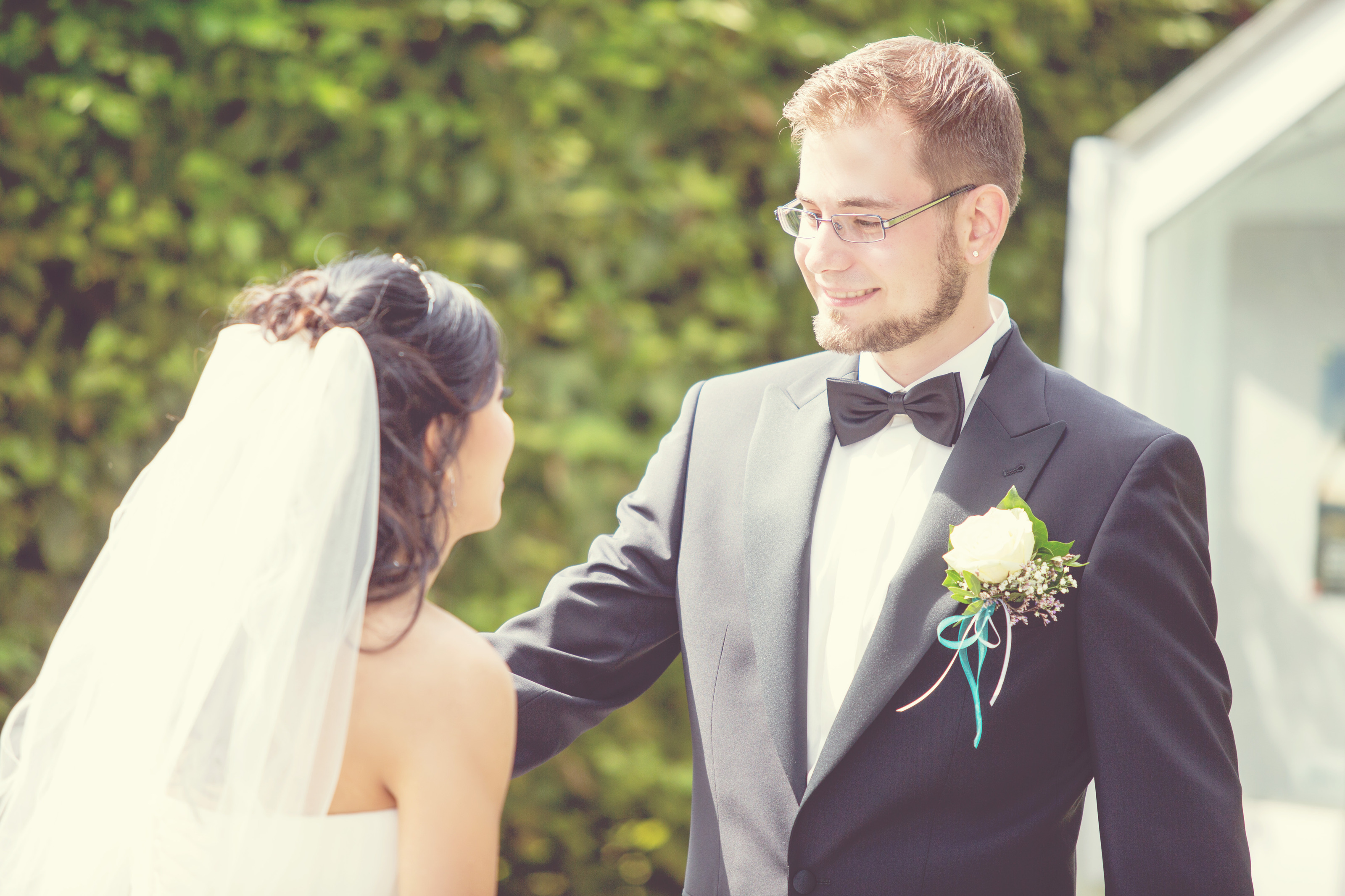 Hochzeitsfotograf Bielefeld – Brautpaar beim First Look, Bräutigam im schwarzen Frack mit Fliege lächelt die Braut an