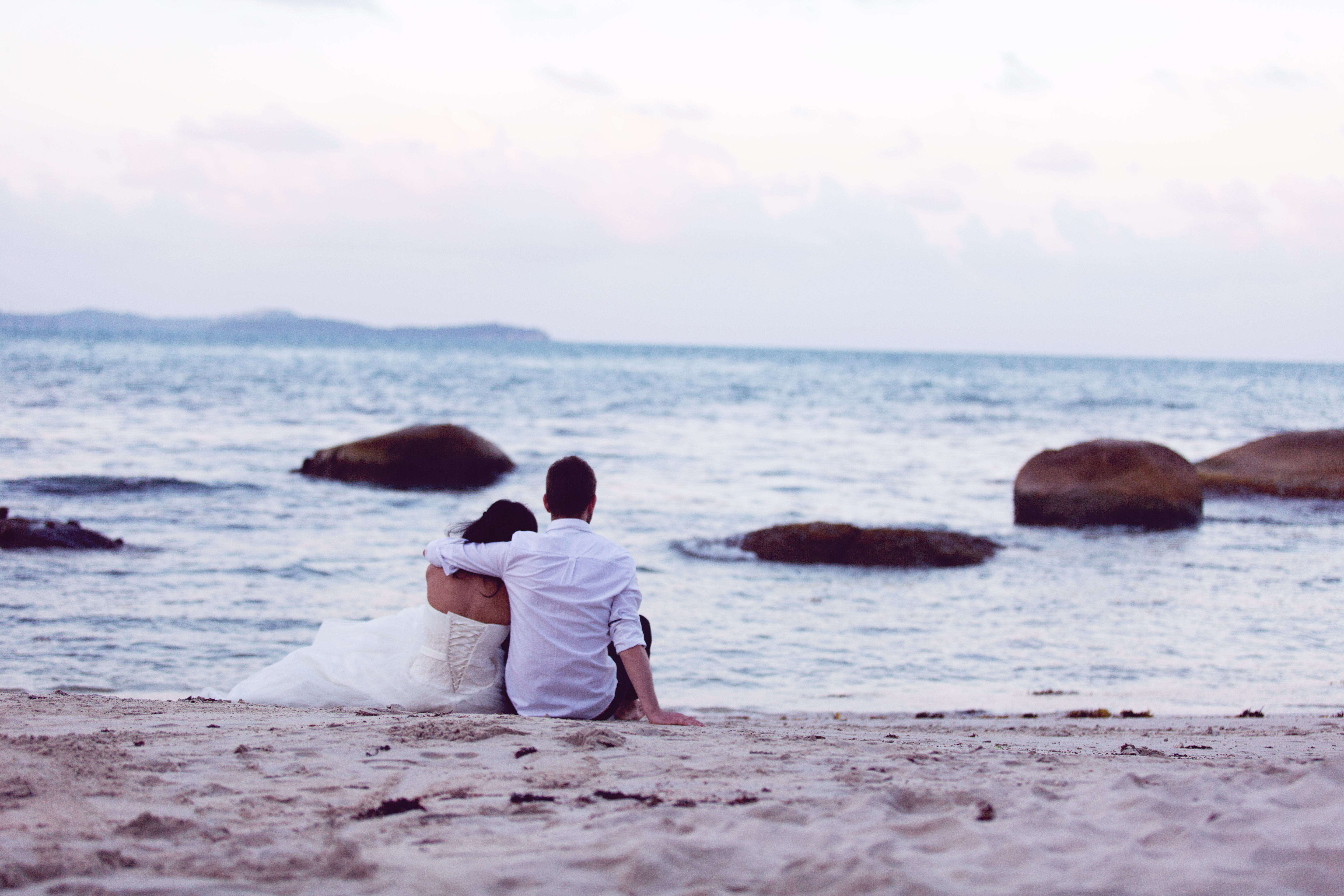 Hochzeitsfotograf Bielefeld – Hochzeitsfotos Thailand, Brautpaar sitzt am Strand von Koh Samui und schaut aufs Meer, Abendstimmung