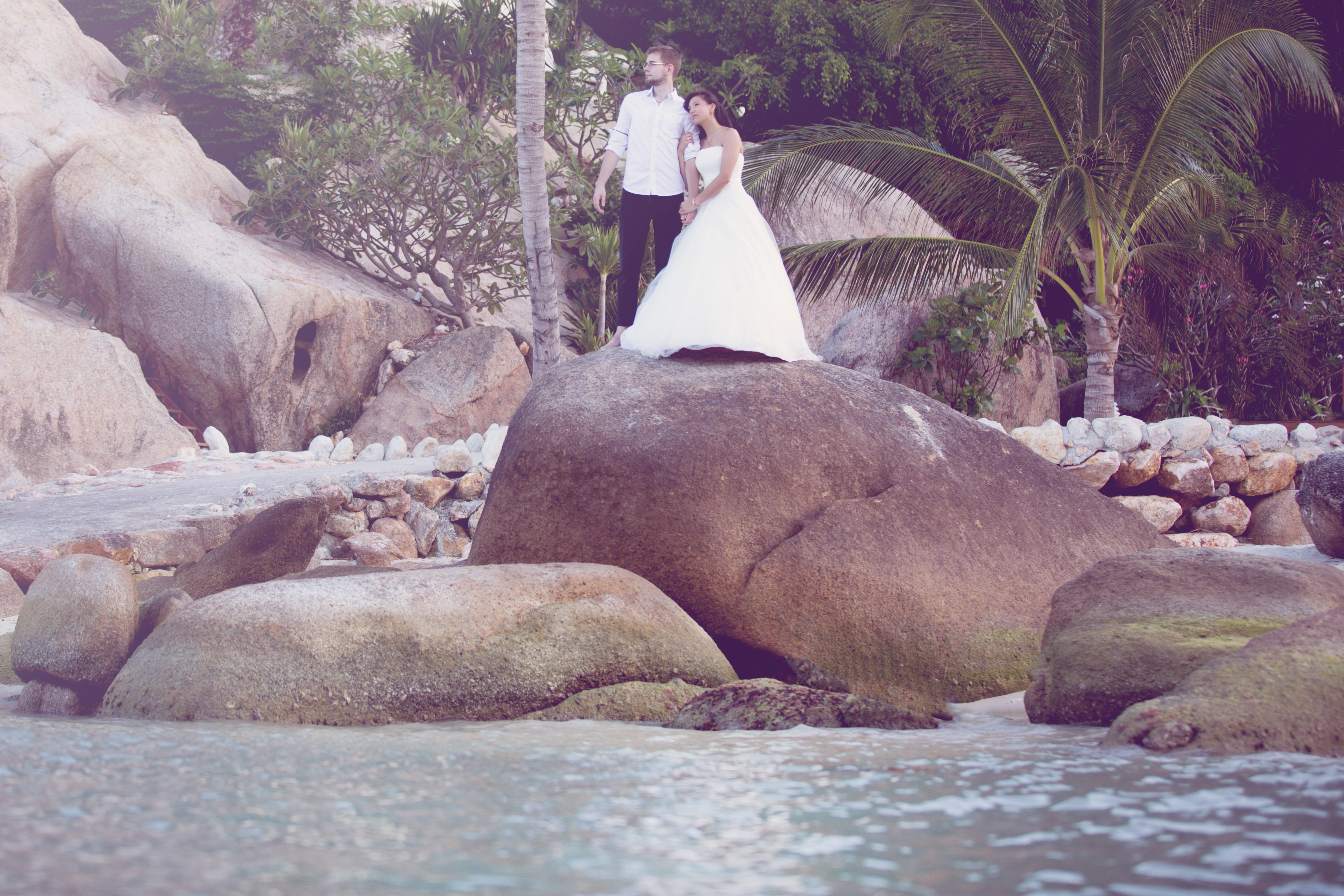 Hochzeitsfotograf Bielefeld – Hochzeitsfotografie Thailand, Brautpaar steht auf Granitfelsen an der Küste von Koh Samui, Braut im weißen Brautkleid